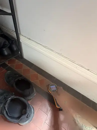 Moisture meter reading 999 REL in the entrance hallway